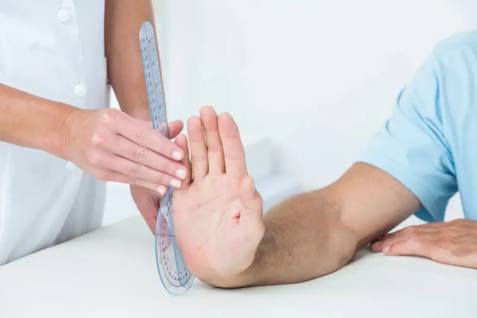 Therapeutin misst die Beweglichkeit eines Handgelenks